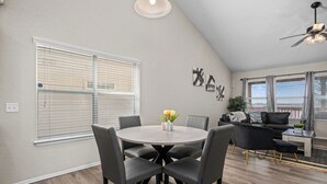 A dining area with a round table and chairs, a ceiling fan, and a living area with a sofa and a coffee table.