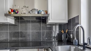 Cuina moderna amb taulell de granat negre, rentamiques d'acer inoxidable i armaris blancs.