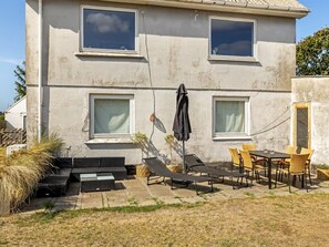 A two-story building with a patio area featuring outdoor furniture and a table.