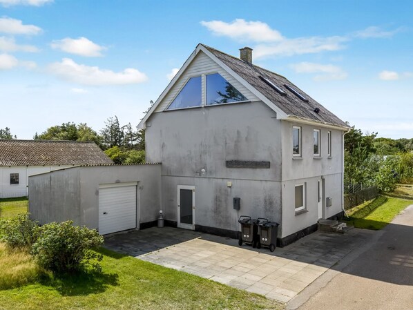 A two-story house with a garage, a small garden, and a clear sky.