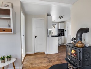 Une cuisine moderne avec un poêle noir, des armoires blanches et un plancher en bois.