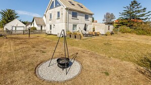 Una casa de dues plantes amb un pati gran, una barbacoa i una zona tancada per una tanca.