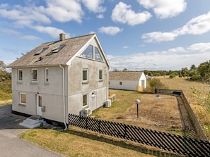 A two-story house with a sloped roof, a fenced yard, and a small adjacent building.