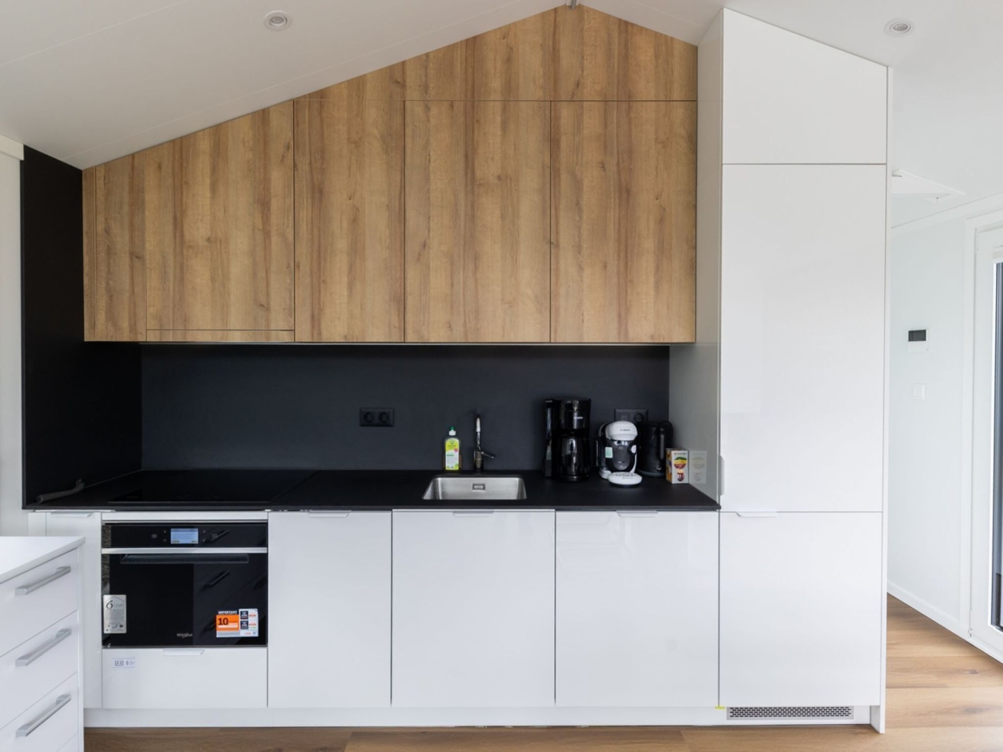 A modern kitchen with wooden cabinets, a black countertop, and a built-in dishwasher.