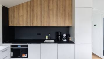 A modern kitchen with wooden cabinets, a black countertop, and a built-in dishwasher.