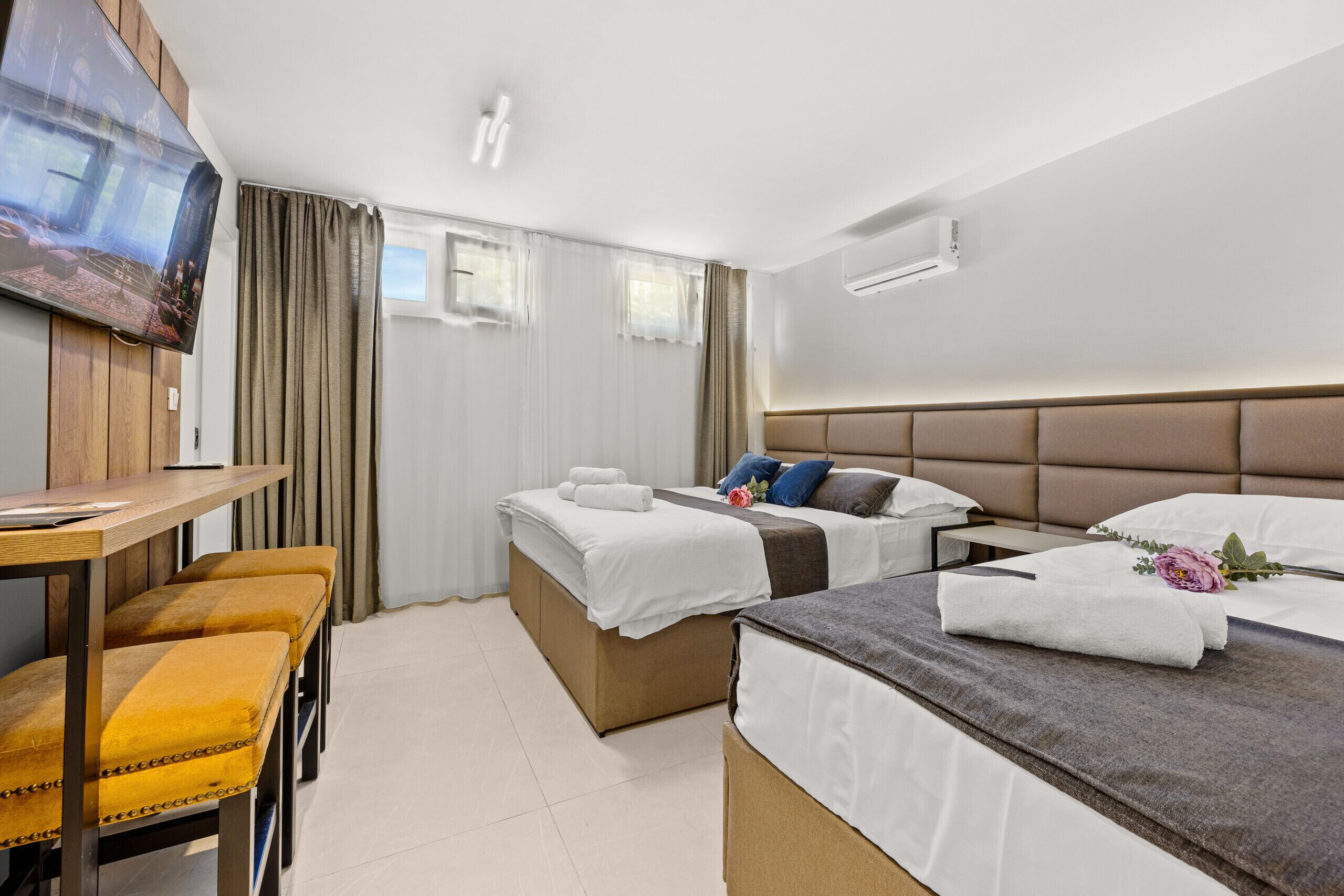 A hotel room with two beds, a desk, and a TV.