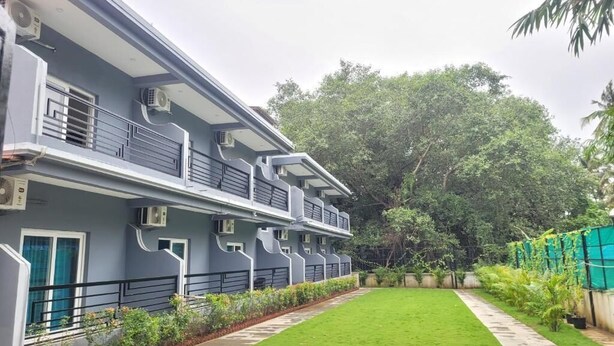 A multi-story building with balconies, air conditioning units, and a well-maintained lawn. - Agusto's Beach Stay (Calangute)