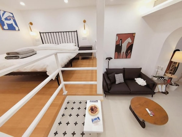 A modern, well-lit room with a bunk bed, a sofa, a coffee table, and a small table with a bowl of fruit.
