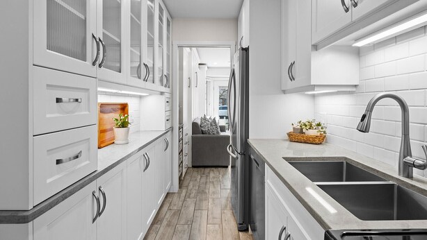 A modern kitchen with white cabinetry, stainless steel appliances, and a central island.