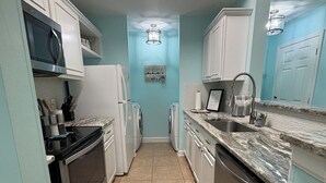 A compact kitchen with white cabinets, a microwave, a refrigerator, and a dishwasher. - Cozy & Peaceful 1- bdrm condo, 4.5 miles to beach, in lovely Gulf Shores (Gulf Shores)