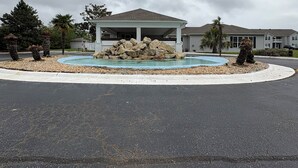 A covered outdoor area with a pool, surrounded by a paved walkway and landscaped with rocks and trees. - Cozy & Peaceful 1- bdrm condo, 4.5 miles to beach, in lovely Gulf Shores (Gulf Shores)