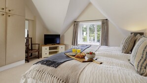Ein Schlafzimmer mit Hochbett, Fernseher, Frühstückstablett und einem fenster mit Vorhängen.