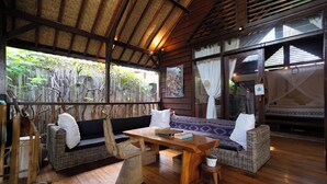 A wooden-floored room with a sofa, a wooden table, and a chair. - Flow Gili Air (Gili Air)