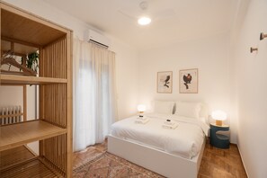 Un dormitorio con cama, lámparas de noche, un armario de madera y un radiador.