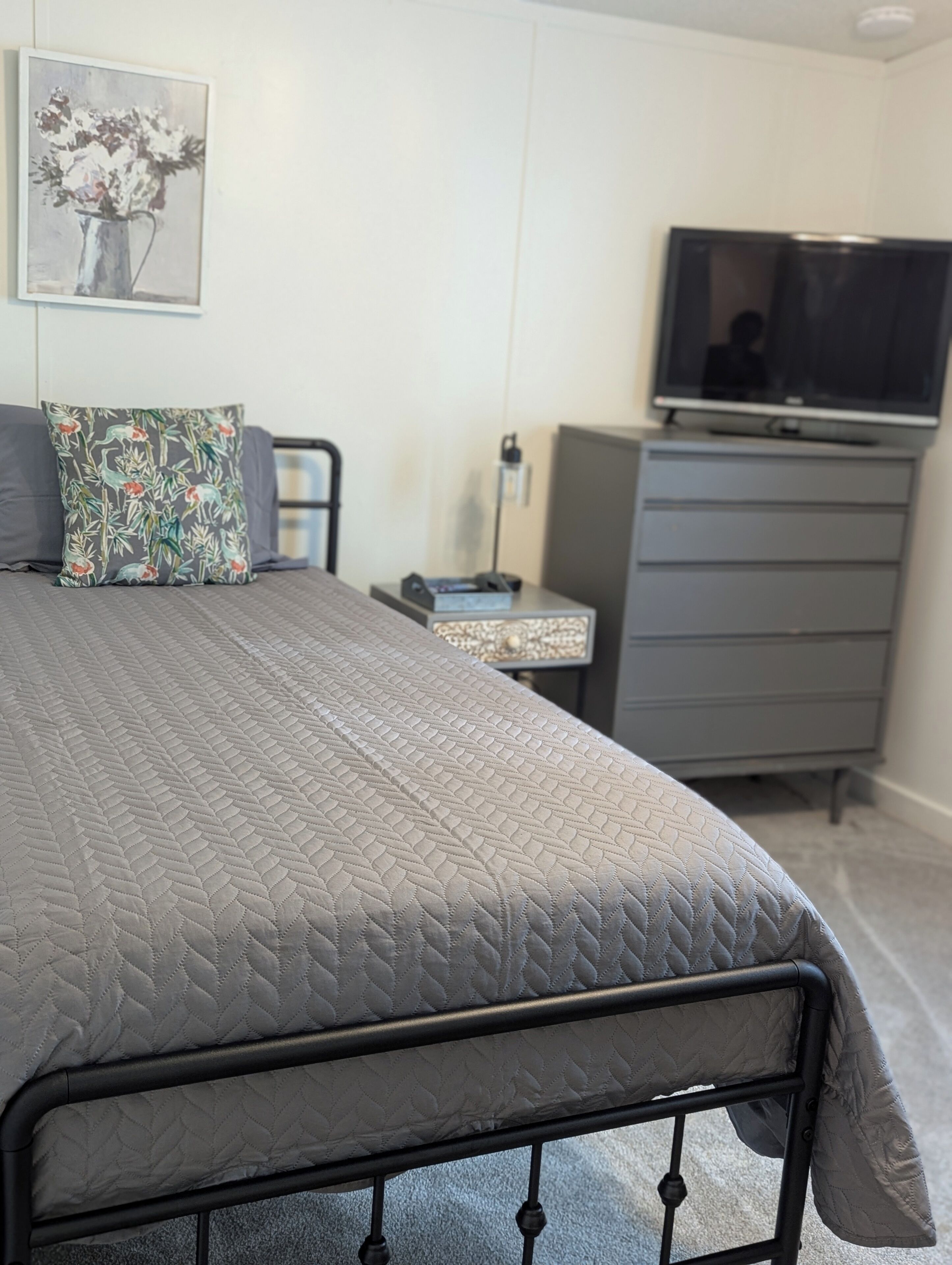 Une chambre bien rangée, avec un lit, une télévision, une commode et une table de chevet.