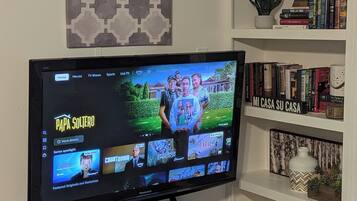 Un televisor de pantalla plana sobre un soporte negro con un estante debajo.