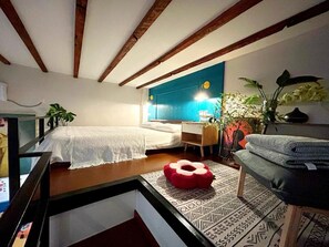 Ein Schlafzimmer mit einem Bett, einem Schreibtisch, einem Stuhl und einem Fenster.