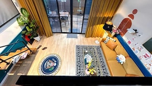 A room with a large window, a sofa, a small table, a decorative rug, and a flag on the wall. - Shanghai Hills& ZINN city bnb (Shanghai)