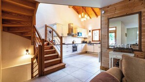 A modern kitchen with white cabinets, a wooden staircase, and a large mirror. - Chalet Abricotine, sleeps 10, Hot tub (Saint-Jean-d´Aulps)