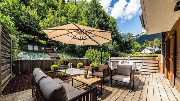 A wooden deck with outdoor furniture, a large umbrella, and a view of a mountain. - Chalet Abricotine, sleeps 10, Hot tub (Saint-Jean-d´Aulps)