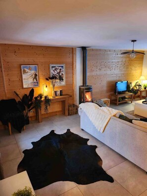 A cozy living room with a fireplace, wooden walls, a television, and a sofa. - Chalet Abricotine, sleeps 10, Hot tub (Saint-Jean-d´Aulps)