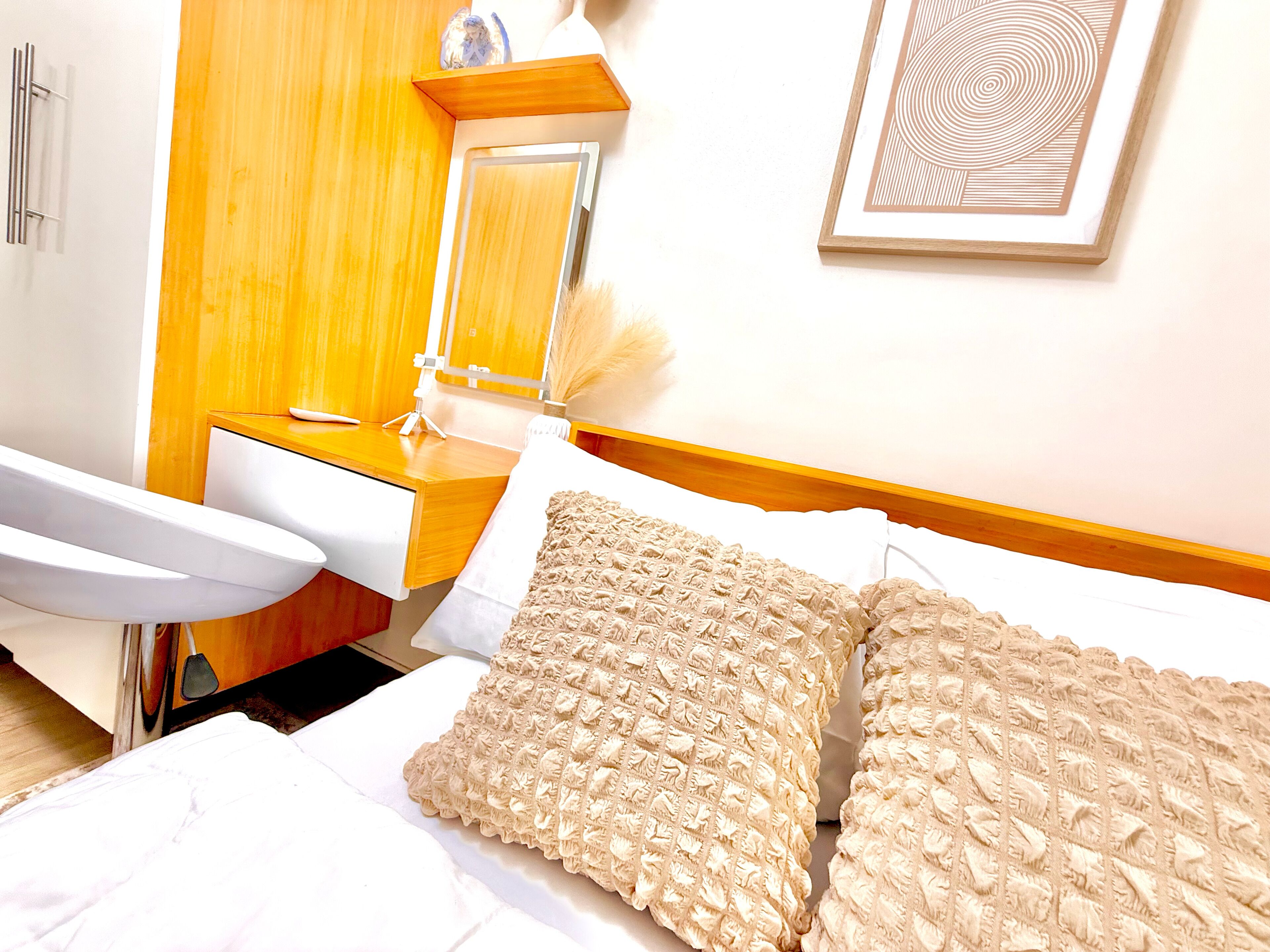 Ein Hotelzimmer mit Bett, Nachttisch, Spiegel und einem gerahmten Kunstwerk an der Wand.