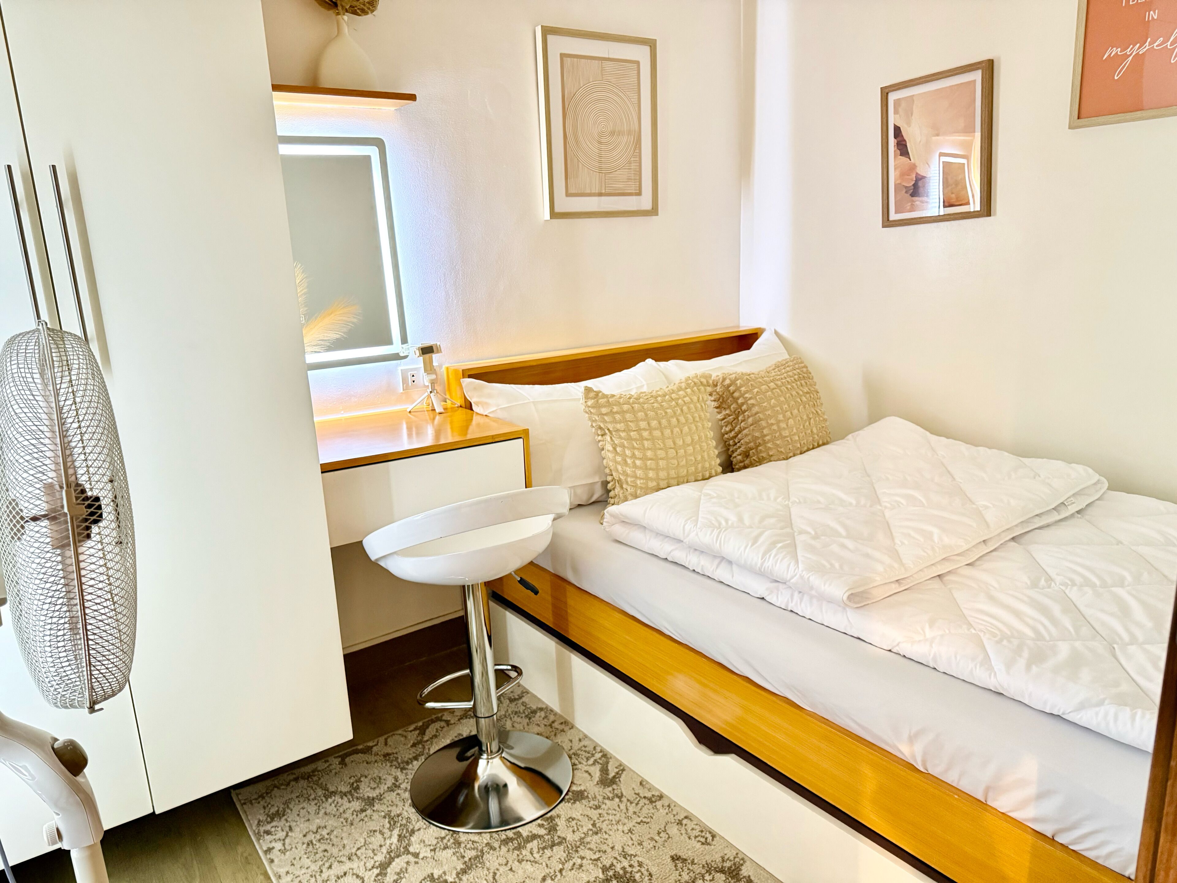 A bedroom with a bed, bedside table, and a mirror.