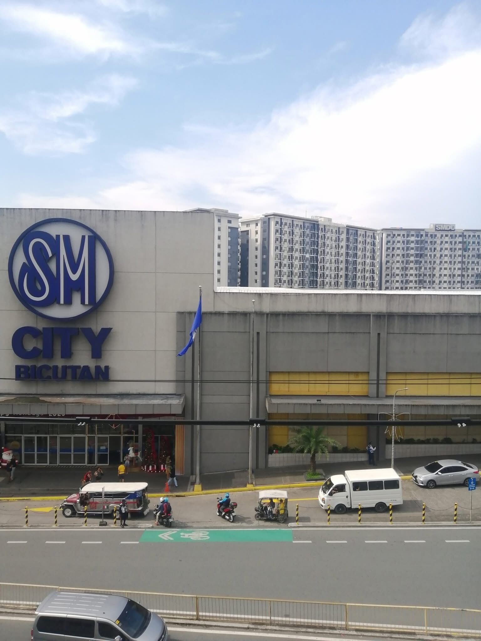 A large building with a prominent 'SM City Bicutan' sign, indicating a commercial complex with multiple floors and a modern architectural design.