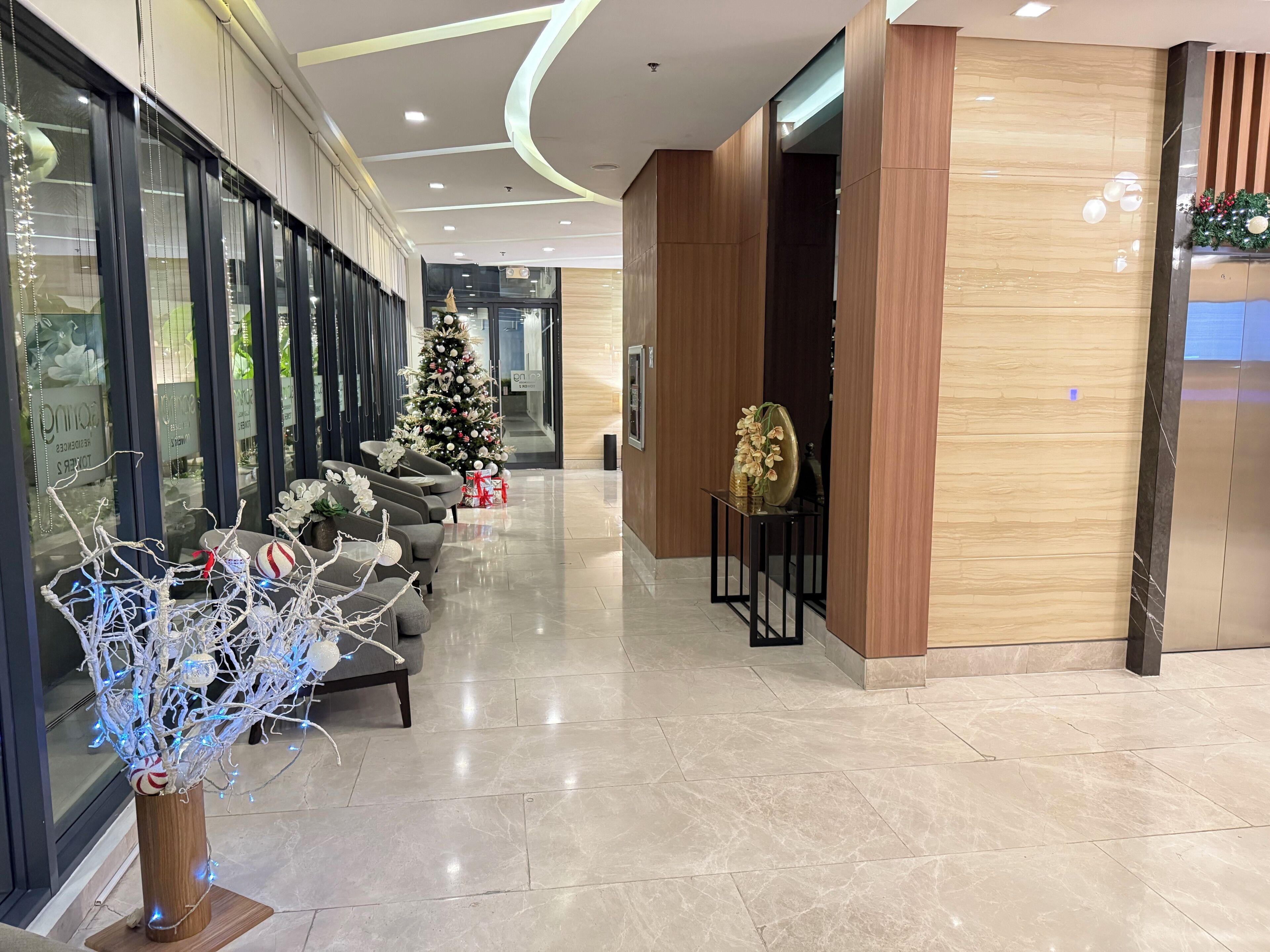 A modern lobby with a Christmas tree, seating area, and a reception desk.