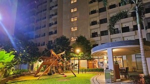 Ein Innenhof mit Spielplatz, überdachter Sitzgelegenheit und einem Gebäude mit mehreren Etagen und Balkonen.