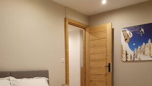 A hotel room with a bed, a wooden door, a night sky painting, and a yellow blanket. - Chalet Clocher Sleeps 10 Hot tub (Essert-Romand)