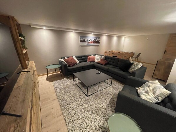 A living room with a sectional sofa, a coffee table, a small round table, and a wooden bench.