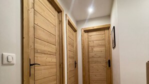 A hallway with wooden doors and a light switch on the wall. - Chalet Clocher Sleeps 10 Hot tub (Essert-Romand)