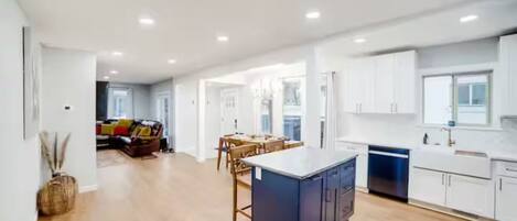 A spacious kitchen with a central island, white cabinetry, and a dining area with a table and chairs.