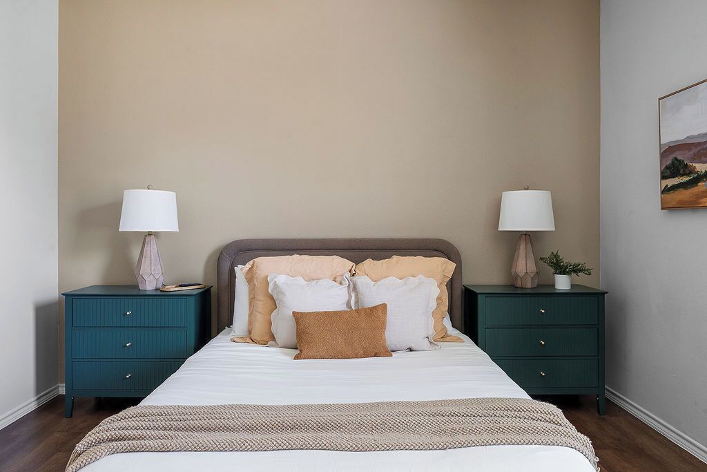 A bedroom with a bed, two nightstands, and a wall-mounted lamp.
