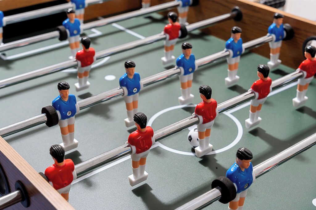 Taula de futbolí amb jugadors uniformats de vermell i blau.