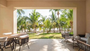 A patio area with a table and chairs, a sofa, and a view of palm trees.