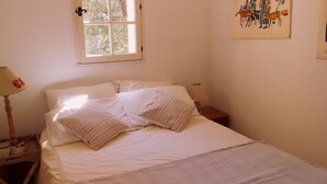 A neatly made bed with white linens and patterned pillows, a bedside lamp, a small bedside table, and a window with a view of trees. - Provencal house with sea view La Croix Valmer "Lou Mamet", ideal for families (La Croix-Valmer)