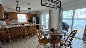 Una cocina moderna con armarios de madera, una mesa de comedor con sillas y vistas a un lago a través de amplios ventanales.