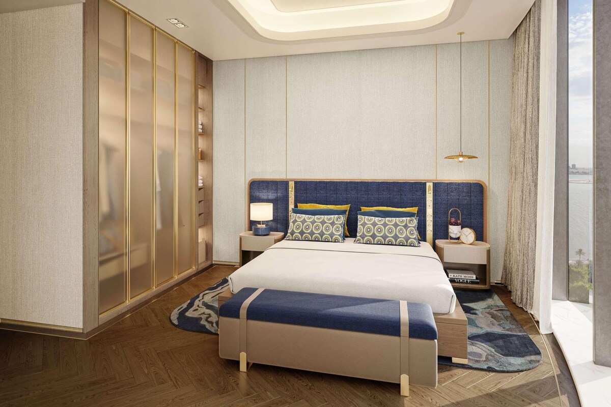 Een moderne slaapkamer met een groot bed, nachtkastjes, een wandklok en een uitzicht op de stad door grote ramen.