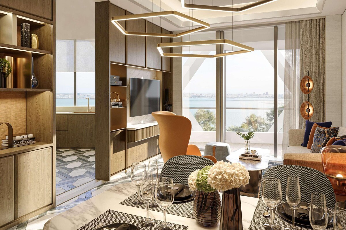 Een moderne woonkamer met een grote televisie, een eethoek met een tafel voor vier personen, en uitzicht op de stad door grote ramen.