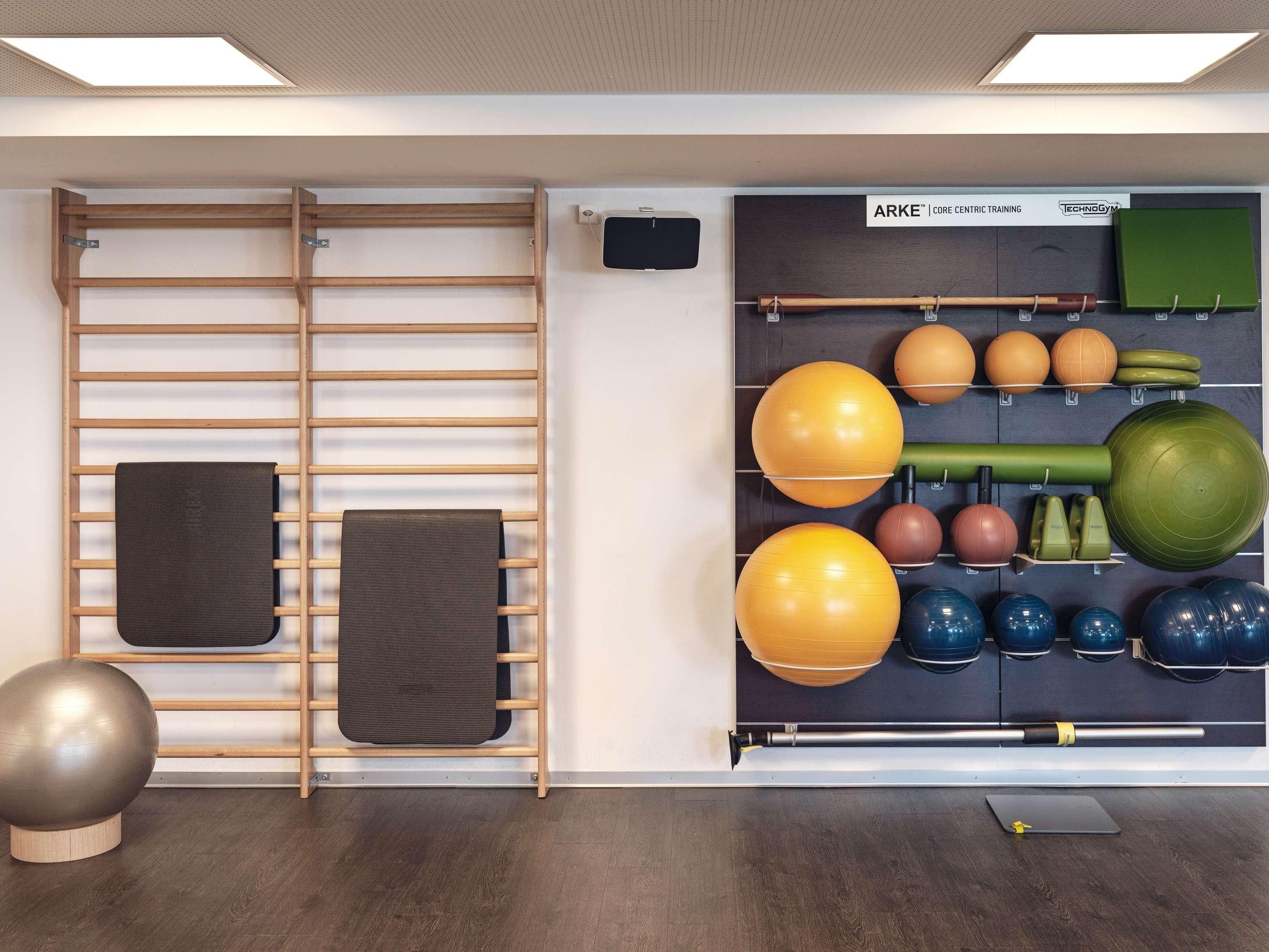 A gym with exercise equipment, including a pull-up bar, medicine balls, and a yoga mat.