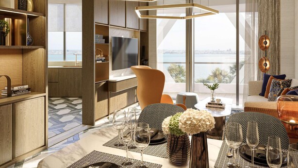 Un salon moderne doté d’un grand téléviseur, d’un coin repas avec une table dressée pour quatre personnes, et offrant une vue sur la ville grâce à de grandes fenêtres.