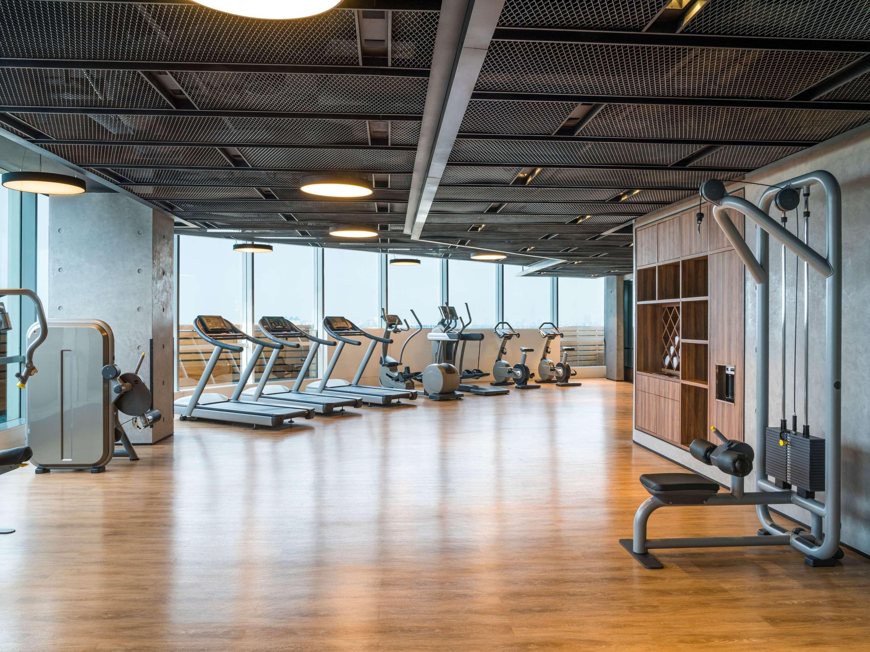 Un gimnasio moderno con cintas de correr, elípticas y equipo de pesas.