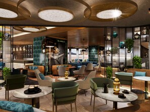 Een moderne lounge met ronde tafels, comfortabele zitplaatsen en sfeervolle verlichting.