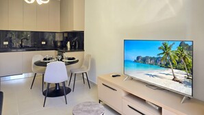 Une cuisine moderne avec un coin repas, un téléviseur diffusant une scène de plage et un luminaire au plafond.