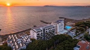 Un hôtel situé sur la côte, avec plusieurs étages, une piscine et une jetée qui s’avance dans la mer.