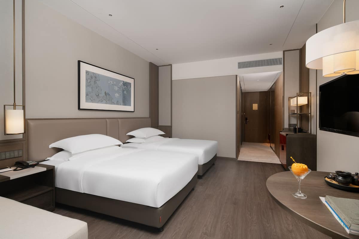 Une chambre d’hôtel avec un lit, une table de chevet, une lampe et un tableau encadré au mur.