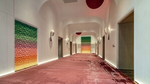 A modern hotel corridor with a red carpet, white walls, and a colorful geometric wall design. - Juntels Panan Jinhua (Jinhua)