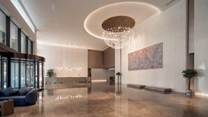 A spacious lobby with a modern chandelier, seating area, and artwork on the walls. - Juntels Panan Jinhua (Jinhua)
